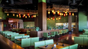 Un restaurante amplio con asientos tipo banqueta verdes y mesas de madera, una zona de bar y un letrero de casino a la vista.