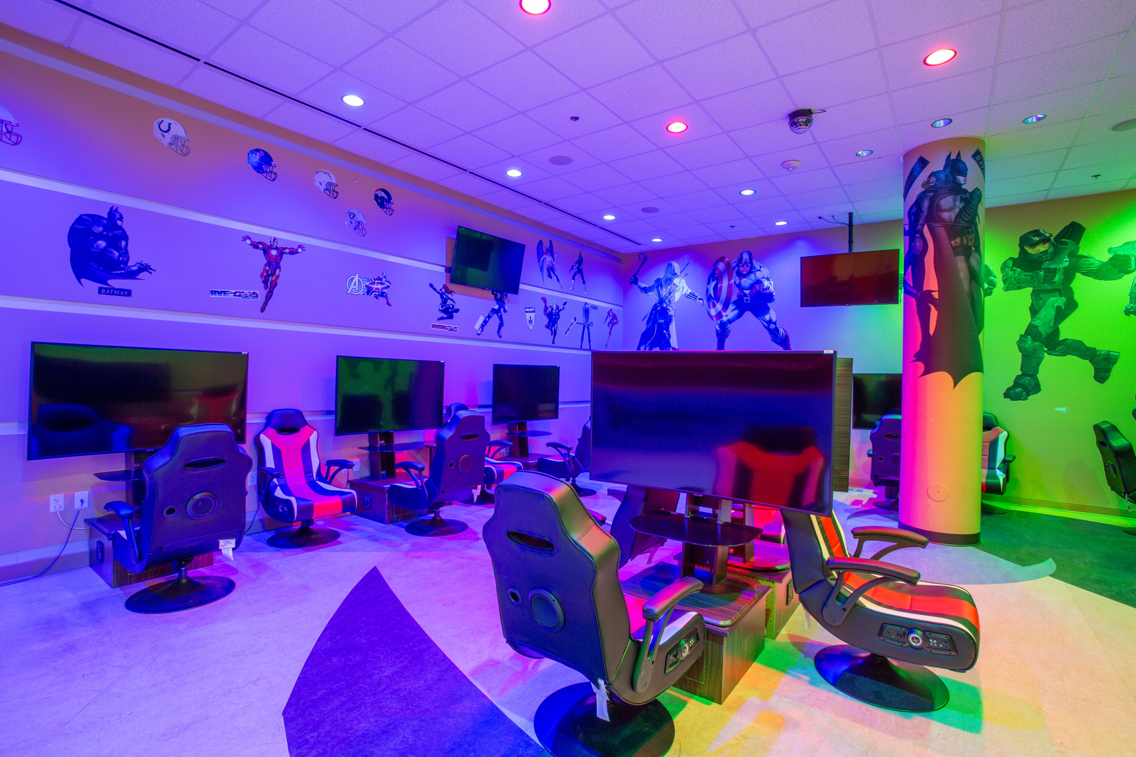 A gaming lounge with multiple gaming stations, each equipped with a monitor and a chair.