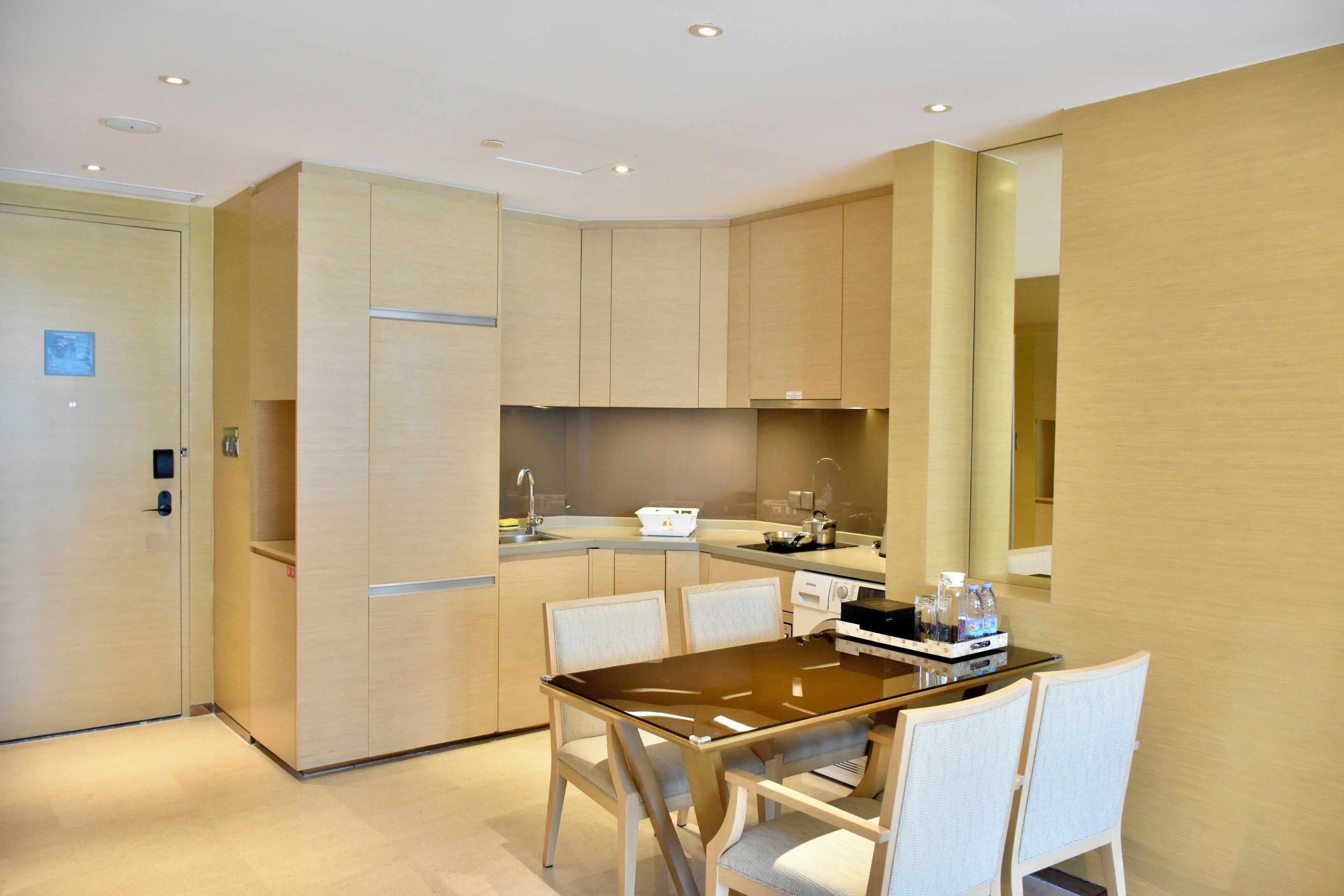 A modern kitchen with wooden cabinets, a dining table with chairs, and a built-in oven.