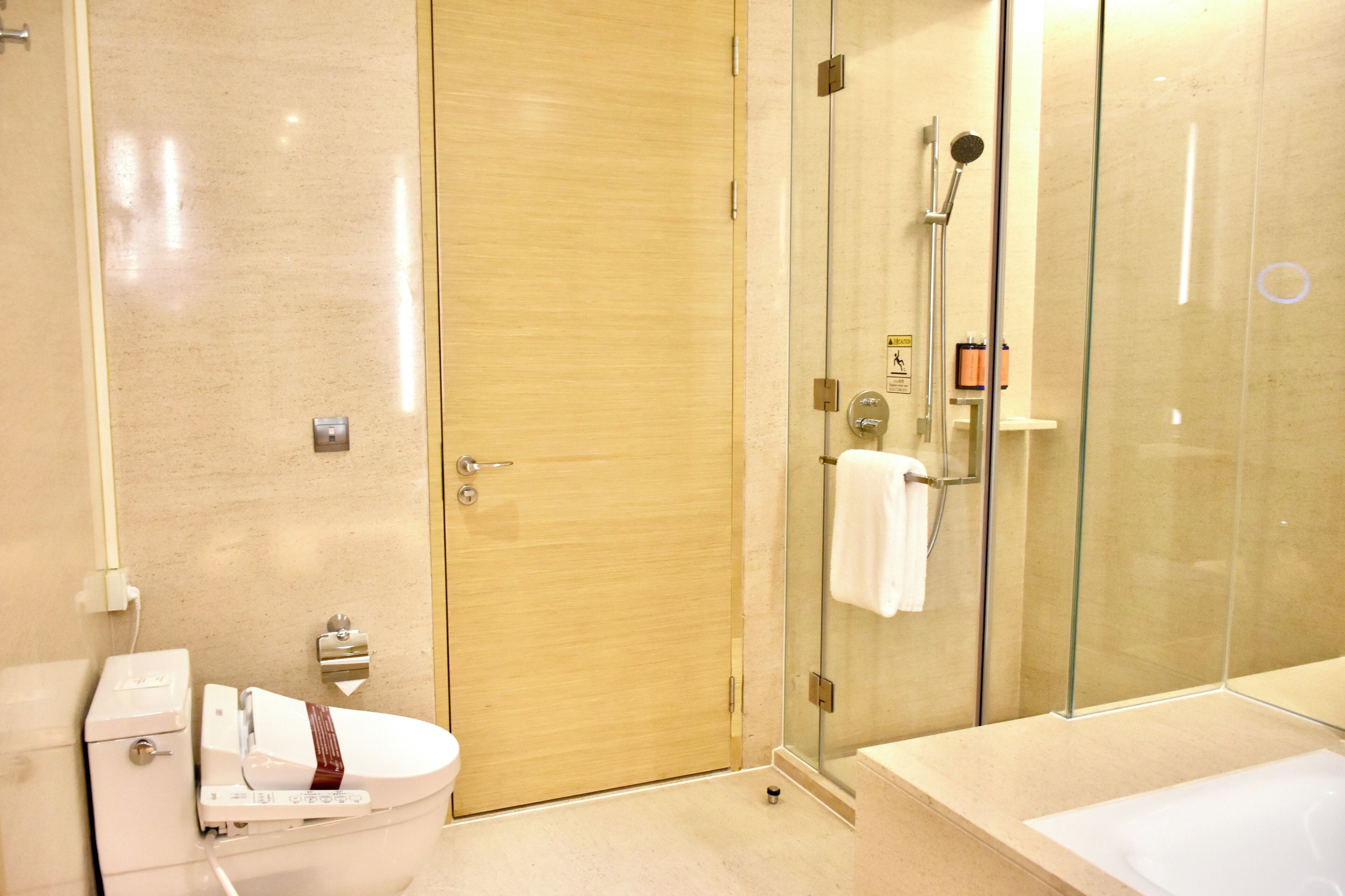 A modern bathroom with a toilet, a glass-enclosed shower, and a bathtub.