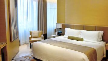 A hotel room with a large bed, a bedside table, a chair, and a window with curtains.