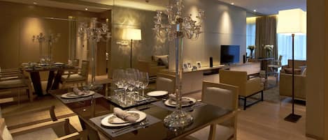 A modern dining area with a glass table set for a meal, surrounded by chairs.