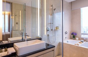 A modern bathroom with a large mirror, a bathtub, a shower, and a vanity with a sink. - Fraser Suites Guangzhou (Guangzhou)