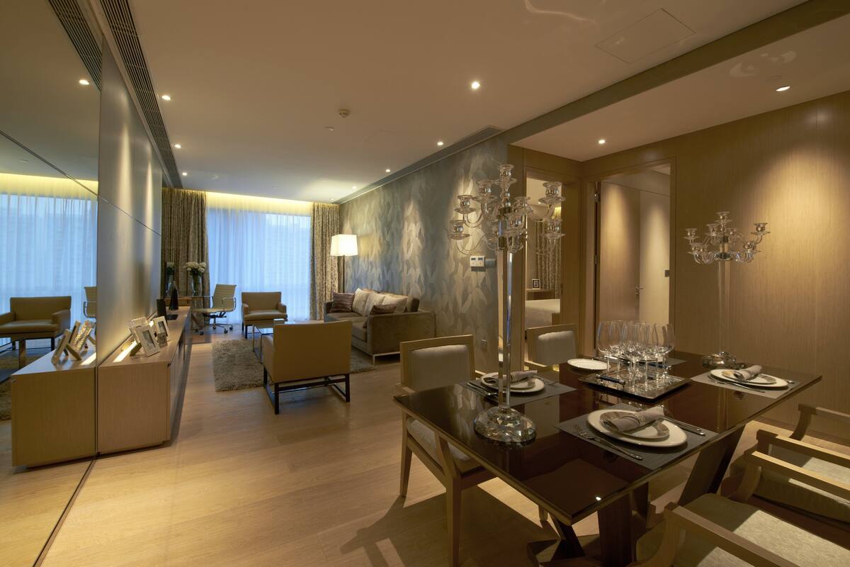 Ett modernt hotellrum med en matplats, ett vardagsrum med soffor och fåtöljer samt en stor spegel.