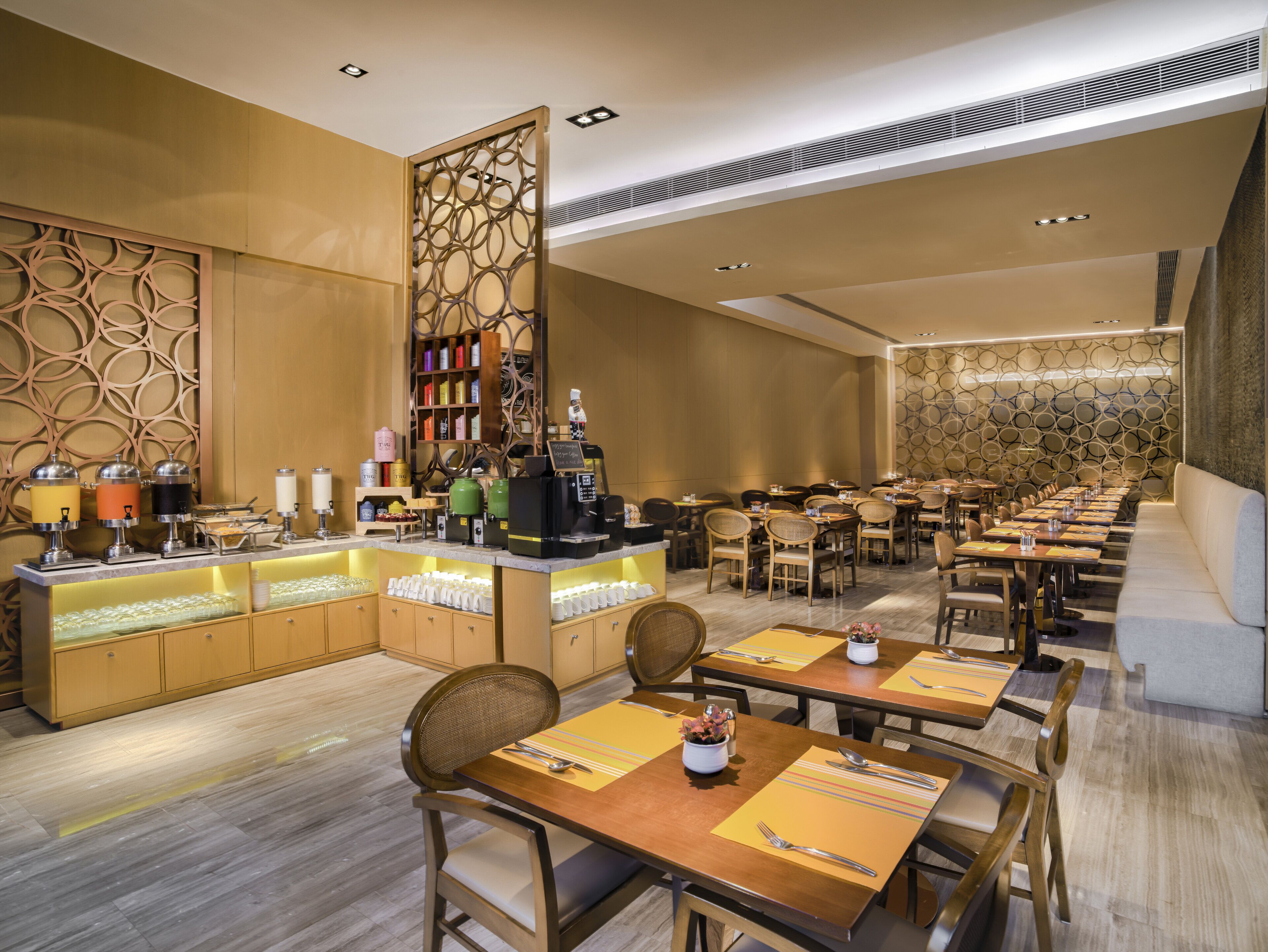 A restaurant with a long counter, multiple tables, and a decorative wall.