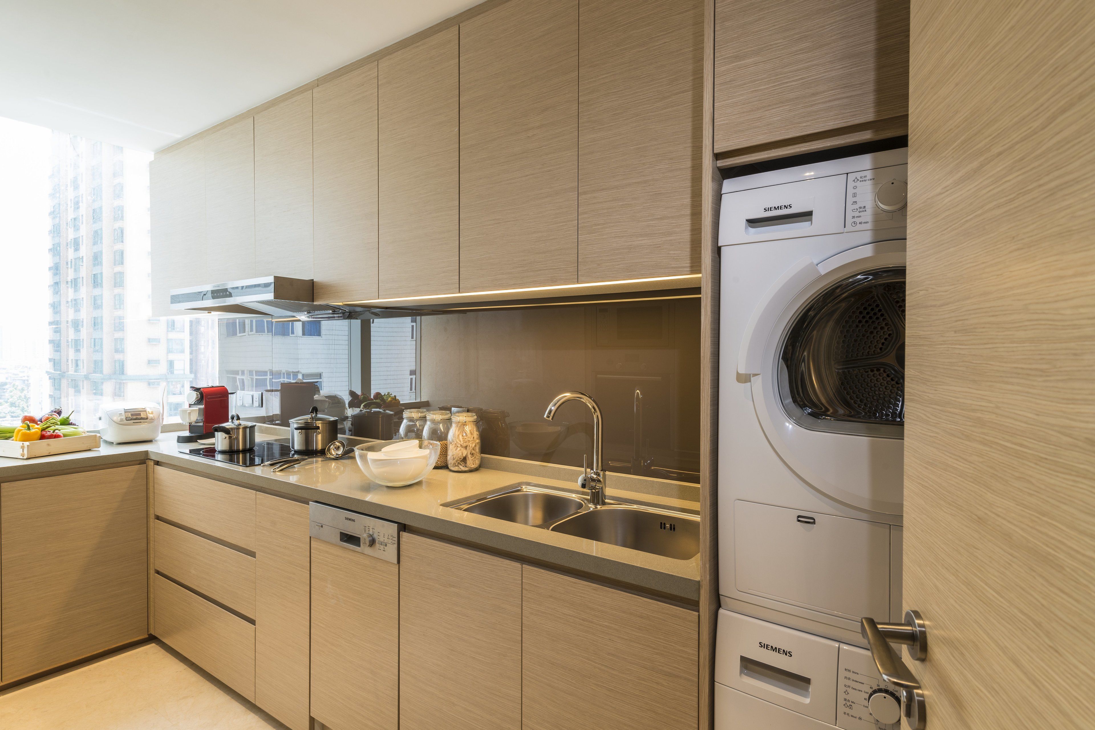 Una cocina moderna con lavadora Siemens integrada, pileta de acero inoxidable y armarios de madera.