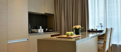 A modern kitchen with a central island, wooden cabinets, and a large window with curtains.