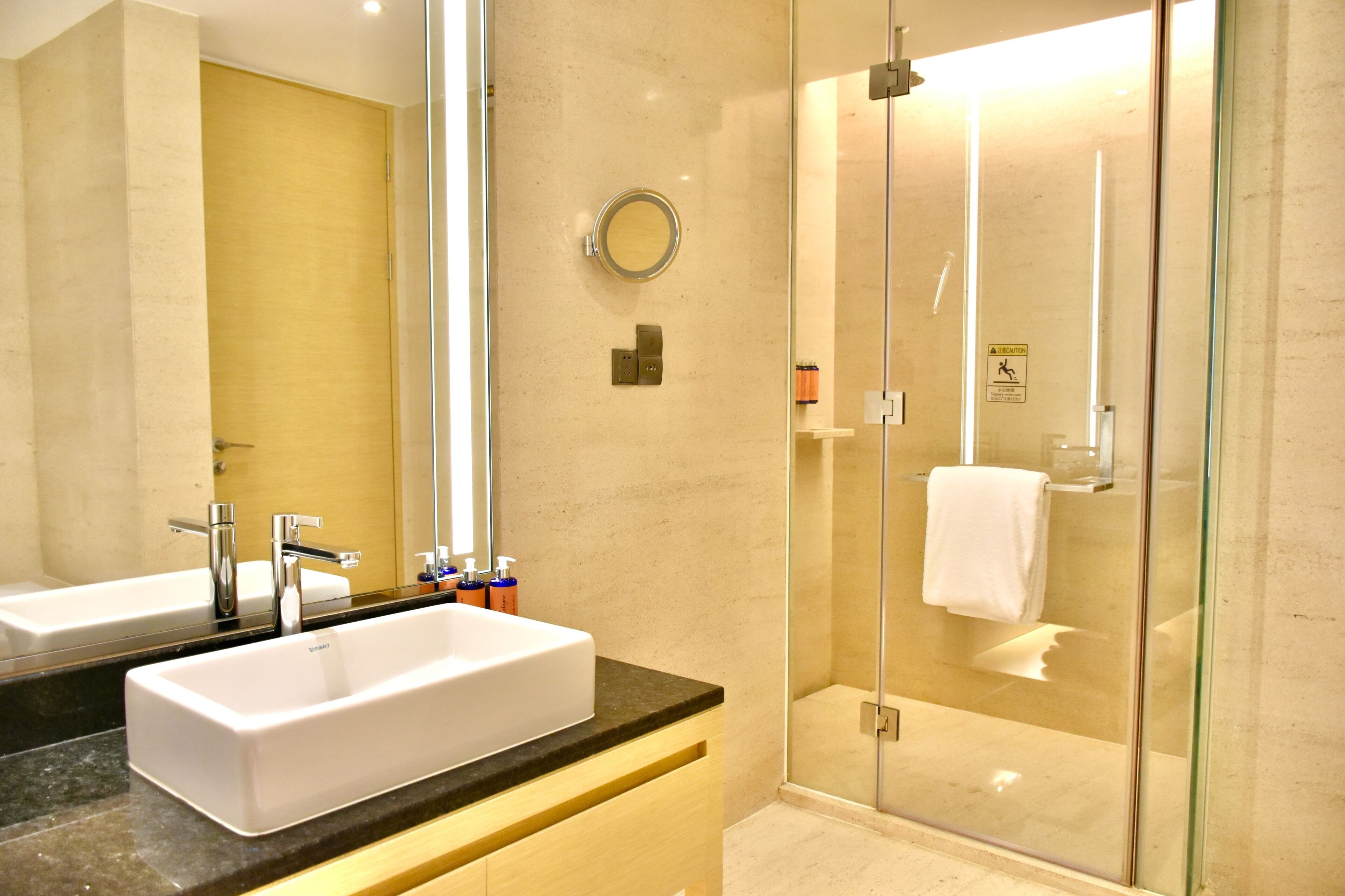 A modern bathroom with a large mirror, two sinks, and a glass-enclosed shower.