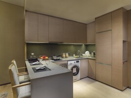 A modern kitchen with a built-in washing machine, a dining area with a table and chairs, and wooden cabinets.