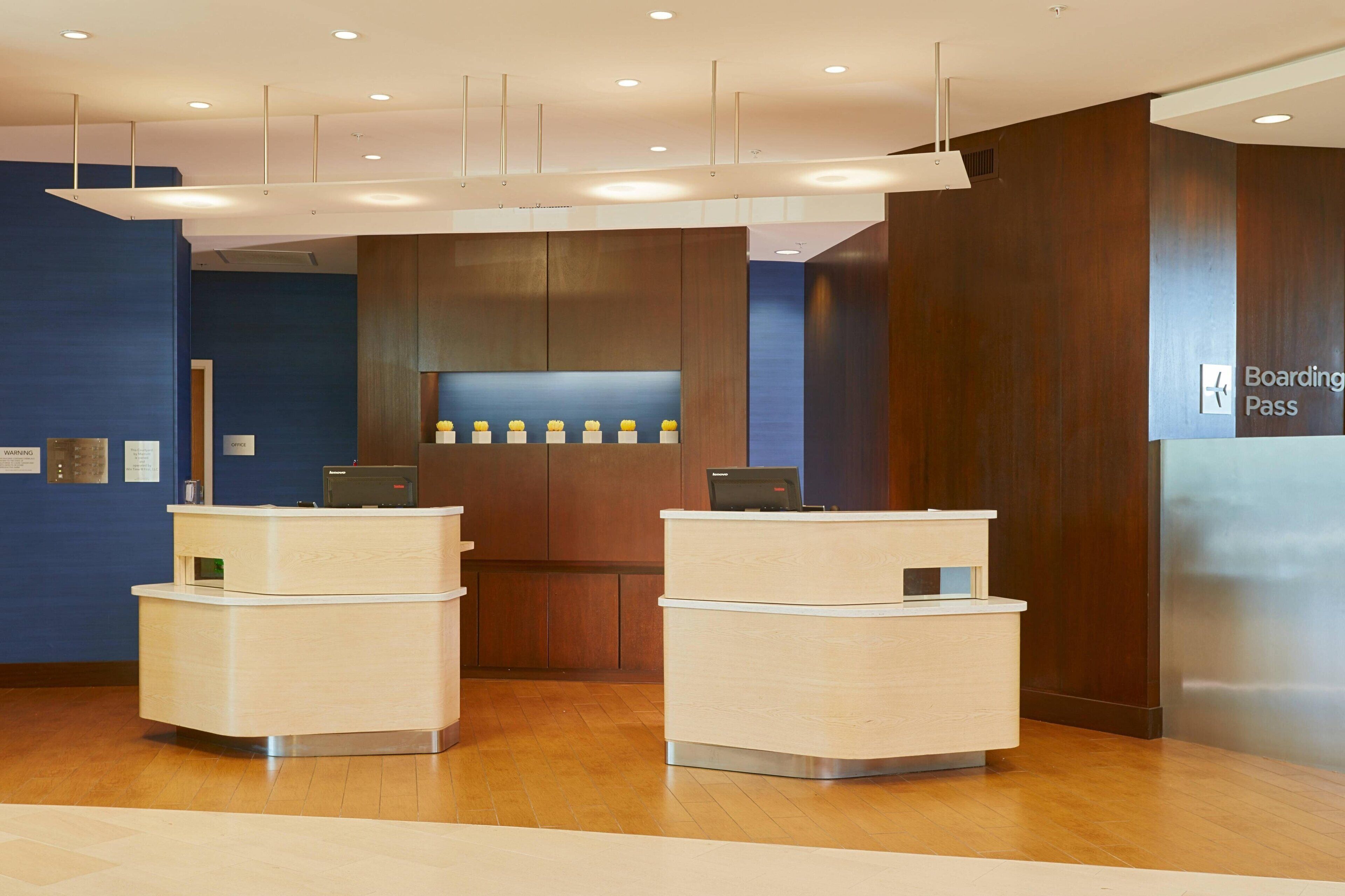 Un área de recepción moderna con dos mostradores, una pared azul y un detalle de panel de madera.
