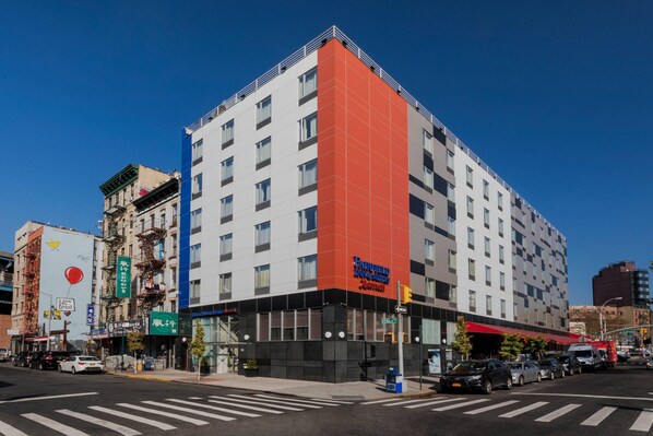 Un hôtel moderne doté d’une façade rouge et blanche remarquable, de plusieurs étages et d’une entrée au niveau du sol avec une façade en verre.