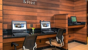 Un espace de travail avec deux ordinateurs portables sur des bureaux, des chaises et un panneau indiquant « Connexion et impression ».