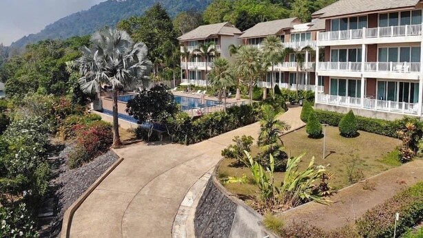 Ein Resort mit mehrstöckigen Gebäuden, einem Pool und üppiger Vegetation.