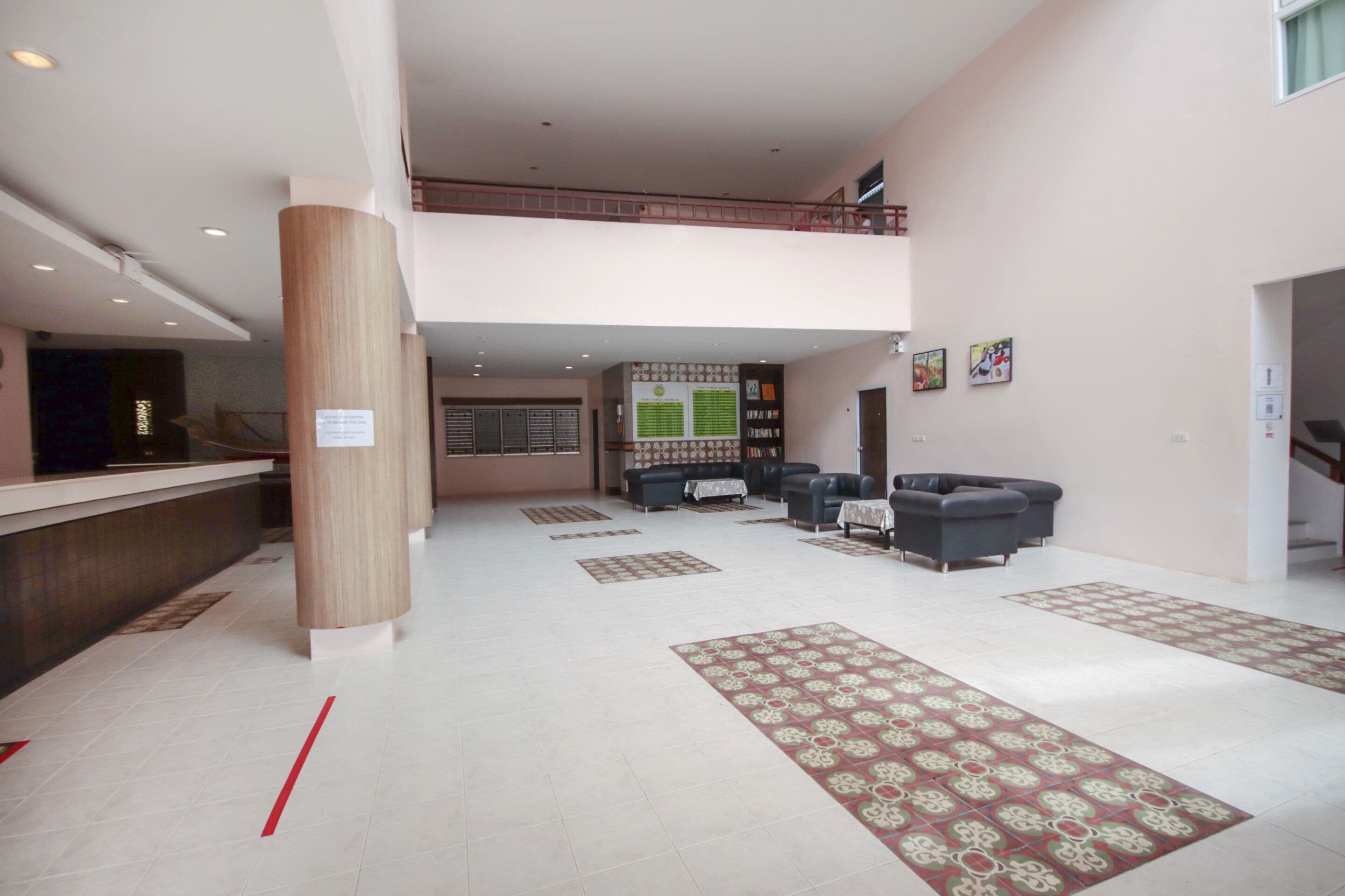 Un vestíbulo amplio con mostrador de recepción, zona de estar y una escalera que conduce a un nivel superior.
