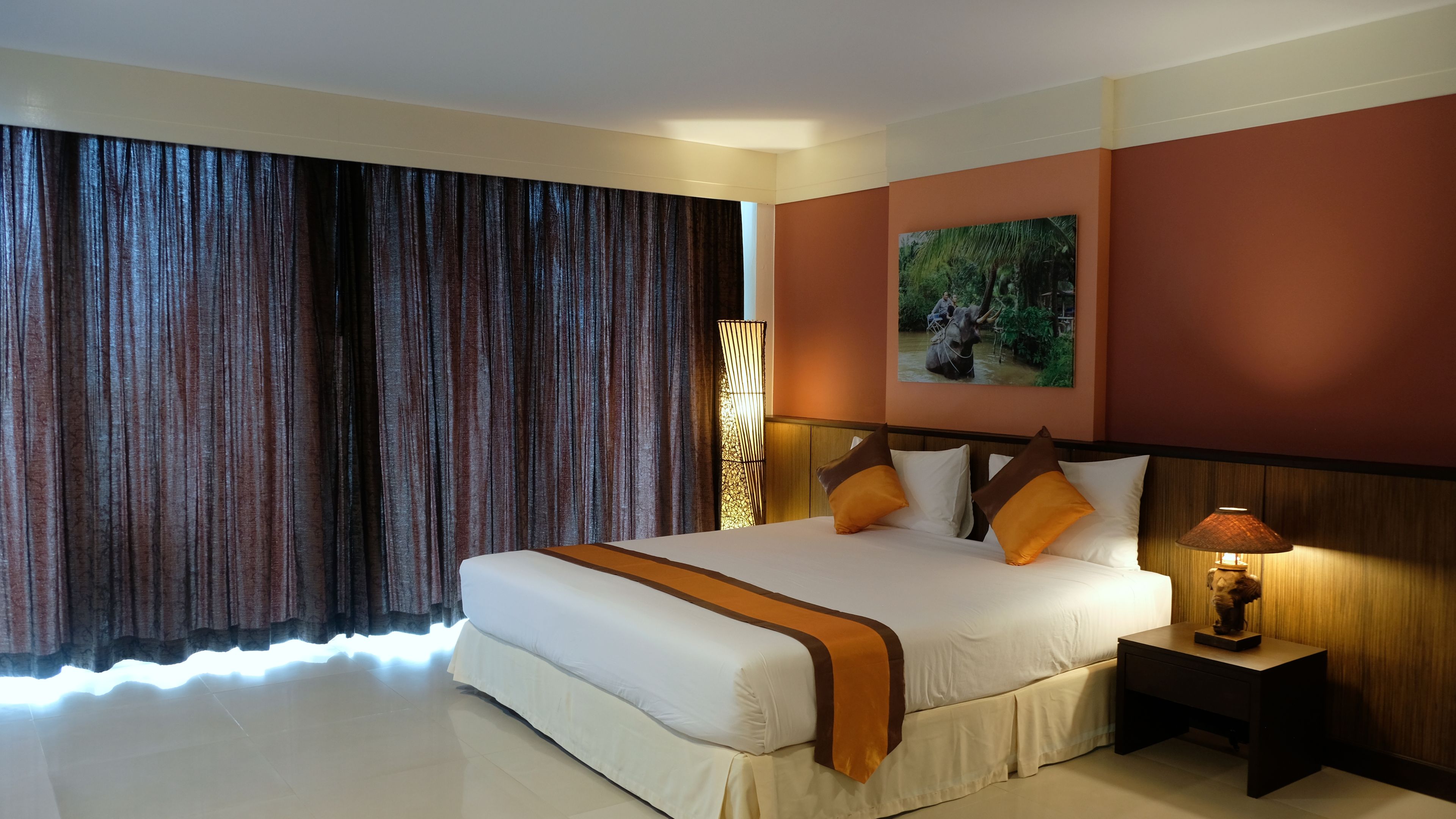 Una camera d'albergo con un letto grande, un comodino, una lampada, un quadro e vista sull'esterno.