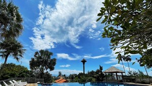 Ein Swimmingpool mit Liegestühlen, einer Laube und einem Turm im Hintergrund.