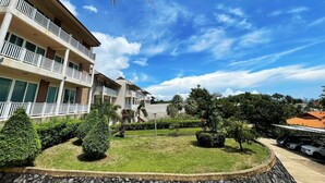 Ein mehrstöckiges Hotel mit Balkonen, einem gepflegten Rasen und einem strahlend blauen Himmel.