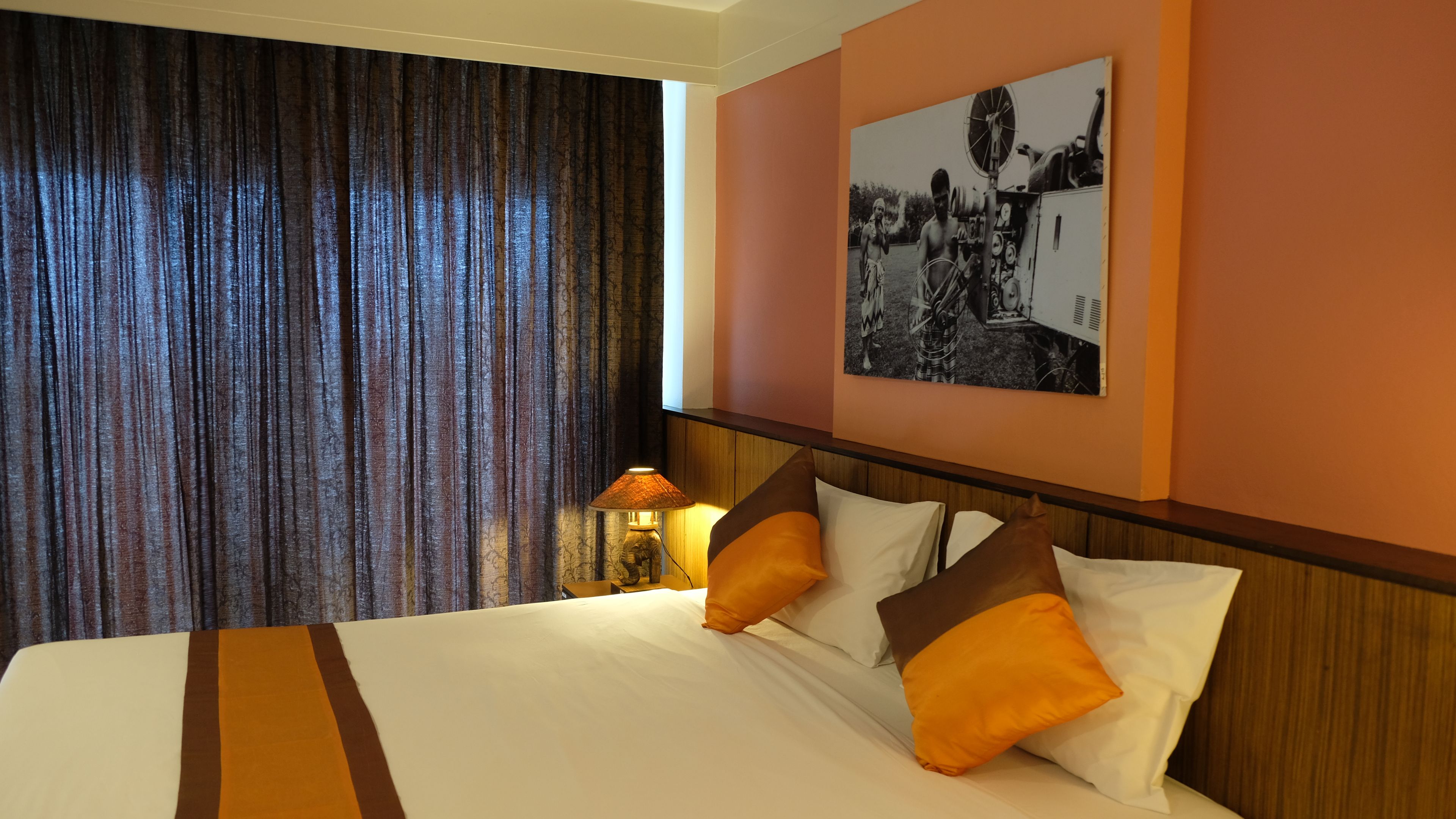 A hotel room with a large bed, a nightstand with a lamp, and a wall-mounted picture.