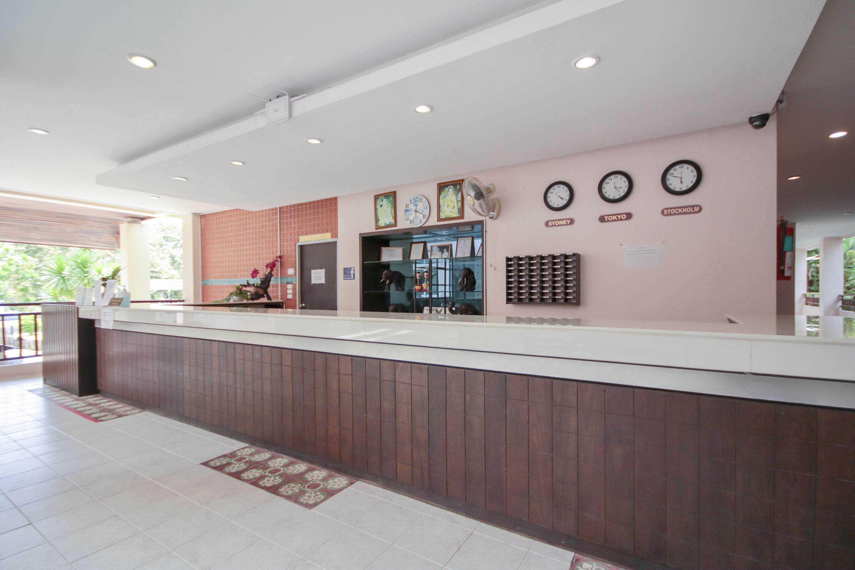 A reception area with a counter, clocks, and a wall-mounted fan.