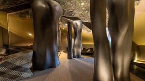 A modern interior with abstract metallic pillars, a patterned woven rug, and a staircase with a unique design. - Figueira by The Beautique Hotels & SPA (Lisbon)