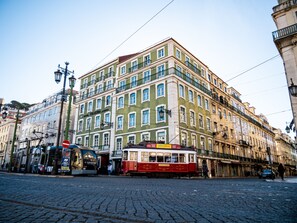 A historic building with multiple floors, large windows, and a red and white tram in front. - Figueira by The Beautique Hotels & SPA (Lisbon)