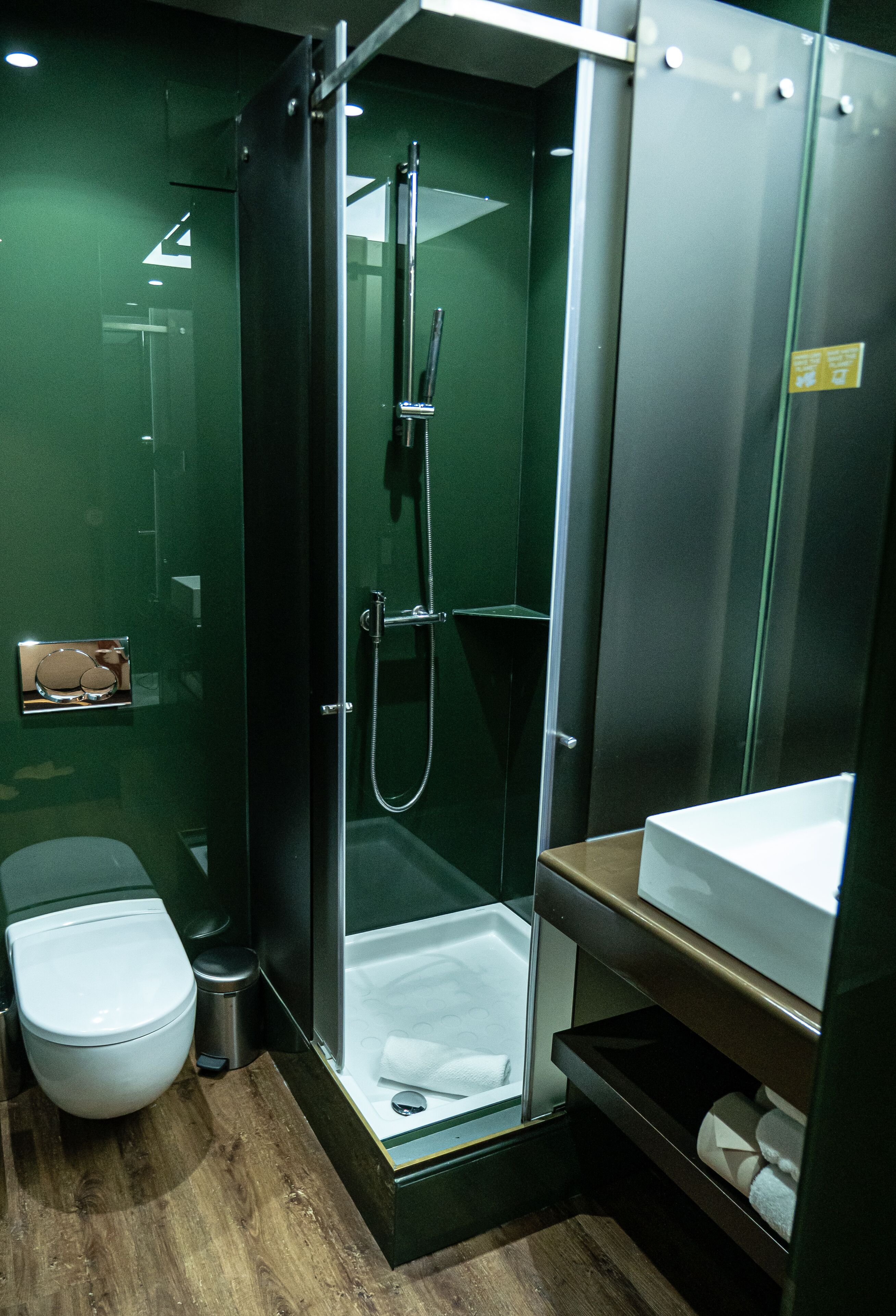 Een kleine badkamer met een douche in een glazen cabine, een toilet en een wastafel.