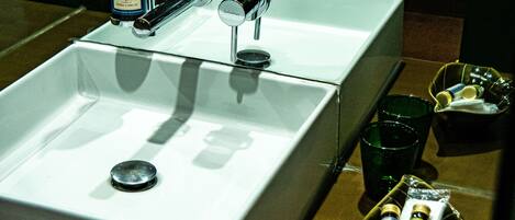 A bathroom with a white sink, two bottles of shampoo, and a small tray with toiletries.