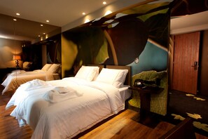 A hotel room with a large bed, a smaller bed, and a bench. There is a painting on the wall and a wooden door. - Figueira by The Beautique Hotels & SPA (Lisbon)