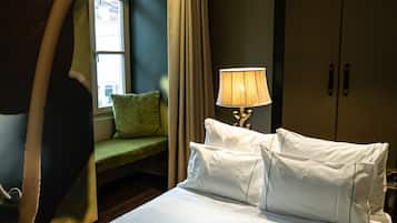 A hotel room with a bed, a lamp, a green chair, and a wardrobe.