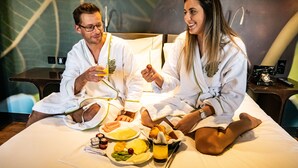 A couple in a hotel room with a bed, breakfast tray, and a telephone. - Figueira by The Beautique Hotels & SPA (Lisbon)