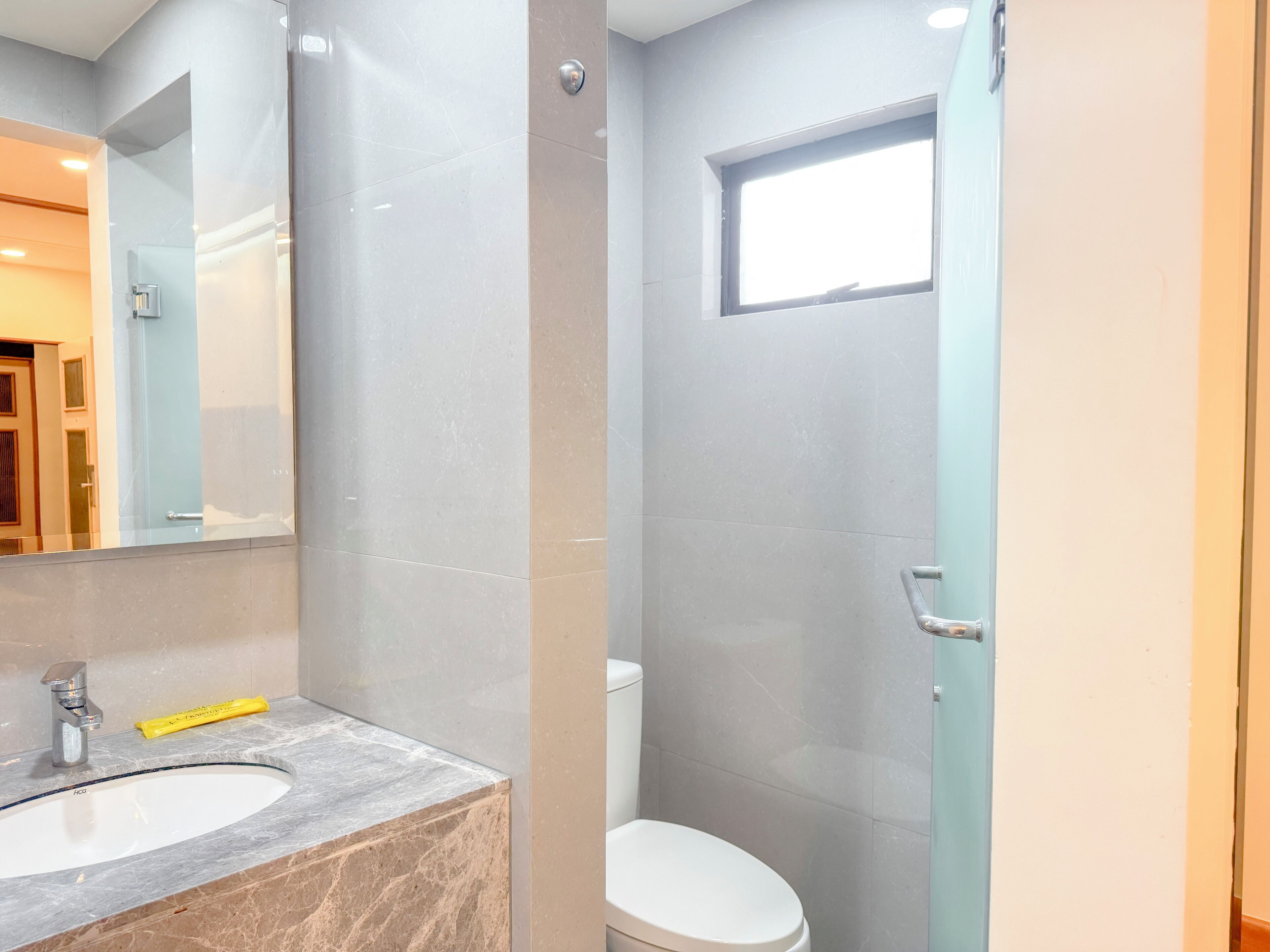 A bathroom with a marble sink, a toilet, and a shower enclosure.