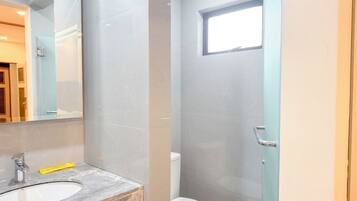 A bathroom with a marble sink, a toilet, and a shower enclosure.