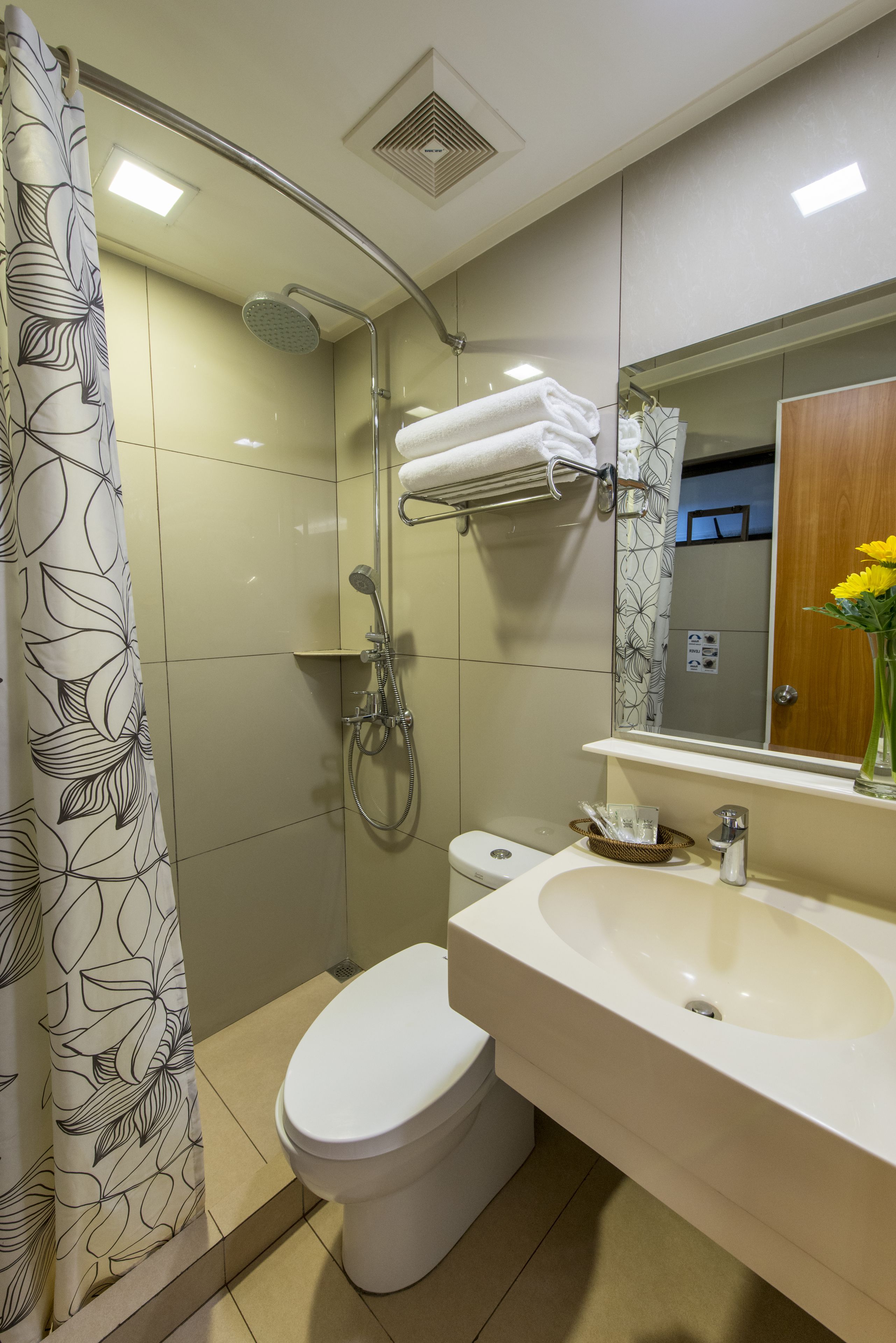 A bathroom with a shower, toilet, sink, and a mirror.