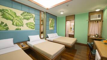 A hotel room with two single beds, a desk with a chair, a small table, and a mirror.