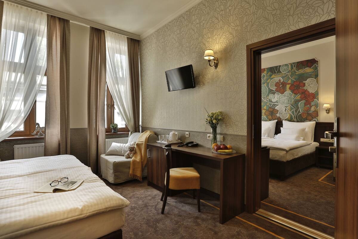 A hotel room with a bed, a desk with a chair, a television, and a mirror.