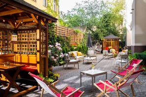 Un espace extérieur aménagé en terrasse, avec des meubles en bois, un belvédère et des plantes en pot.