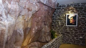 A stone wall with a framed portrait and a large rock structure. - Hotel L'Antic Portal (Vilafames)