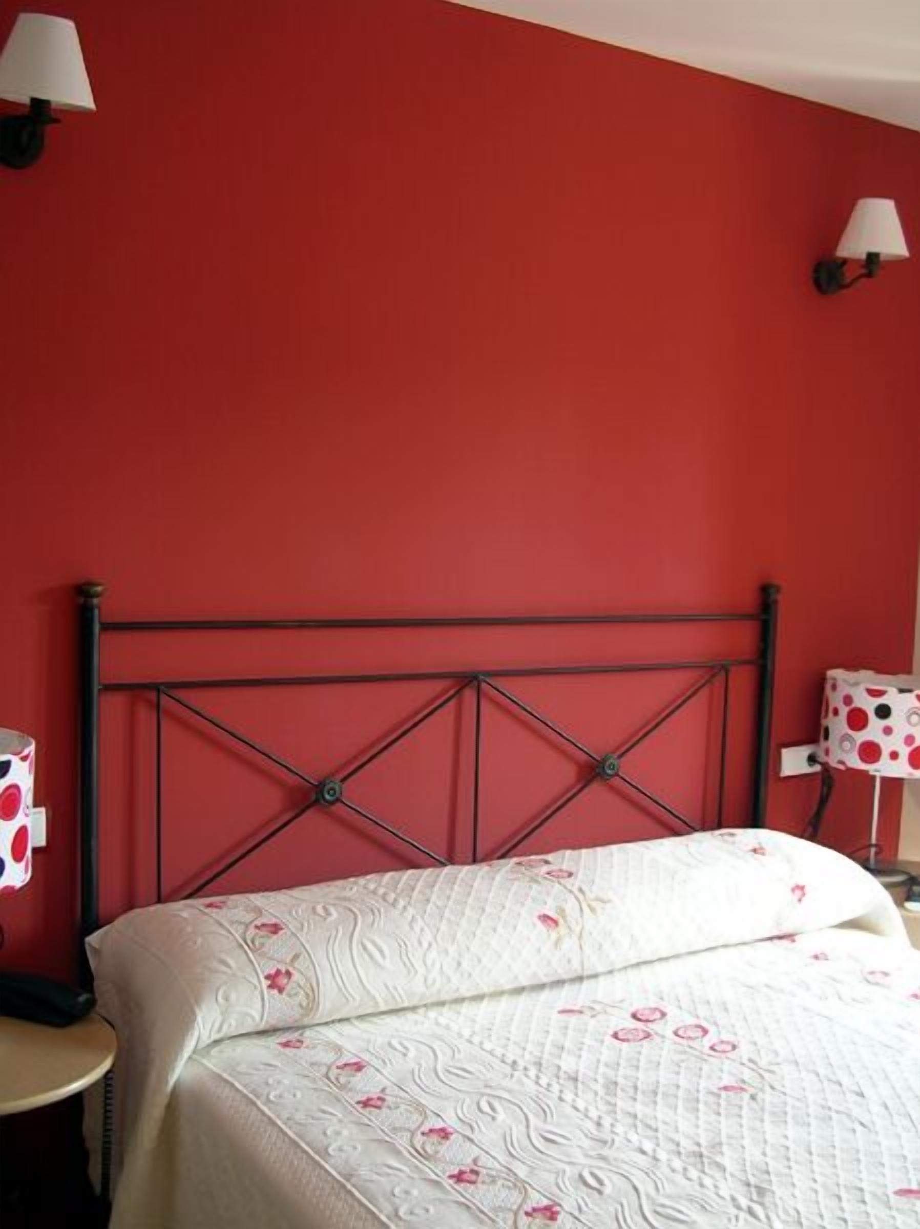 A bed with a quilted headboard, a bedside table, and two wall-mounted lamps.