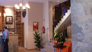 A lobby with a stone wall, a chandelier, a staircase with blue lights, and a fire extinguisher. - Hotel L'Antic Portal (Vilafames)