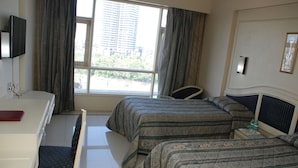Habitación de hotel con dos camas, un escritorio, una silla, un televisor y una ventana con cortinas.