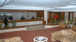 Zona de recepción de un hotel, con mostrador de recepción, área de espera con sofás y un mostrador de atención al cliente.