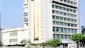 Un edificio alto de varios pisos con fachada blanca y numerosas ventanas.