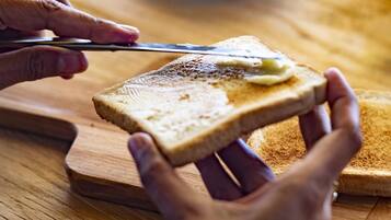 A person spreading butter on toast on a wooden table.