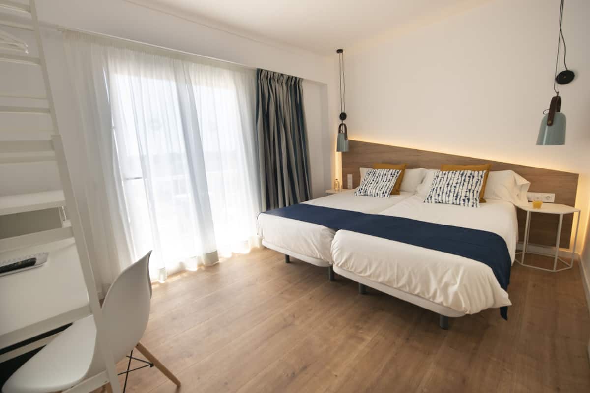 A modern hotel room with a large bed, a desk, and a chair.