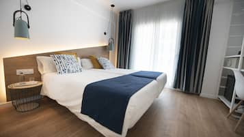 A modern hotel room with a large bed, bedside tables, a wardrobe, and a view of the outdoors.