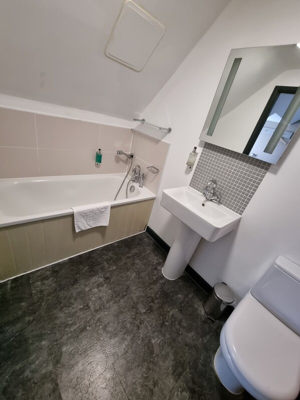 Un baño con bañera, lavamanos e inodoro.