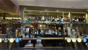 A bar with multiple liquor taps and a variety of bottles. - The Red Lion (Cambridge)