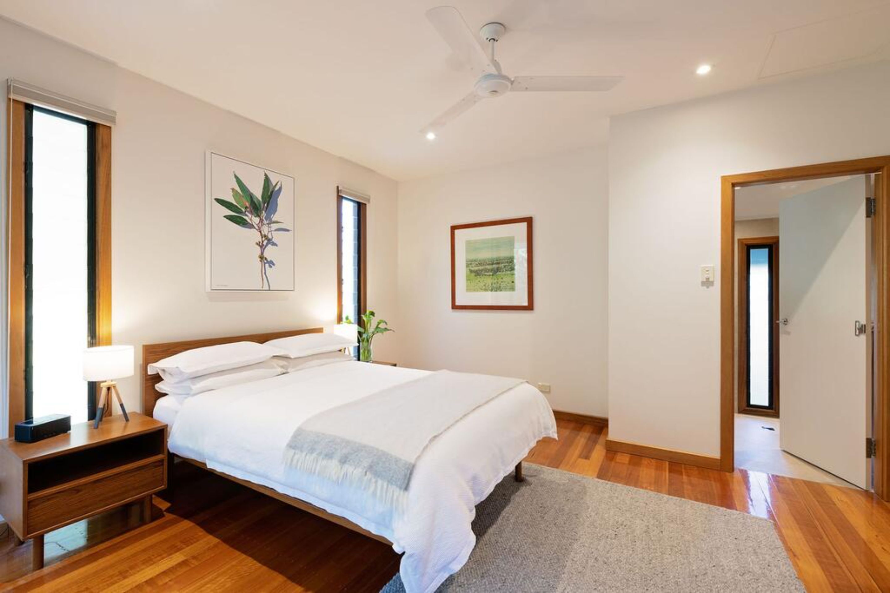 Ein Schlafzimmer mit Bett, Nachttisch, Lampe und Deckenventilator.
