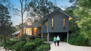 Ein modernes Haus mit einer großen Veranda, umgeben von üppigem Grün und Bäumen.