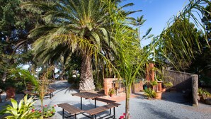 A patio area with a gravel surface, wooden benches, and potted plants. - Modra's Apartments (Tumby Bay)